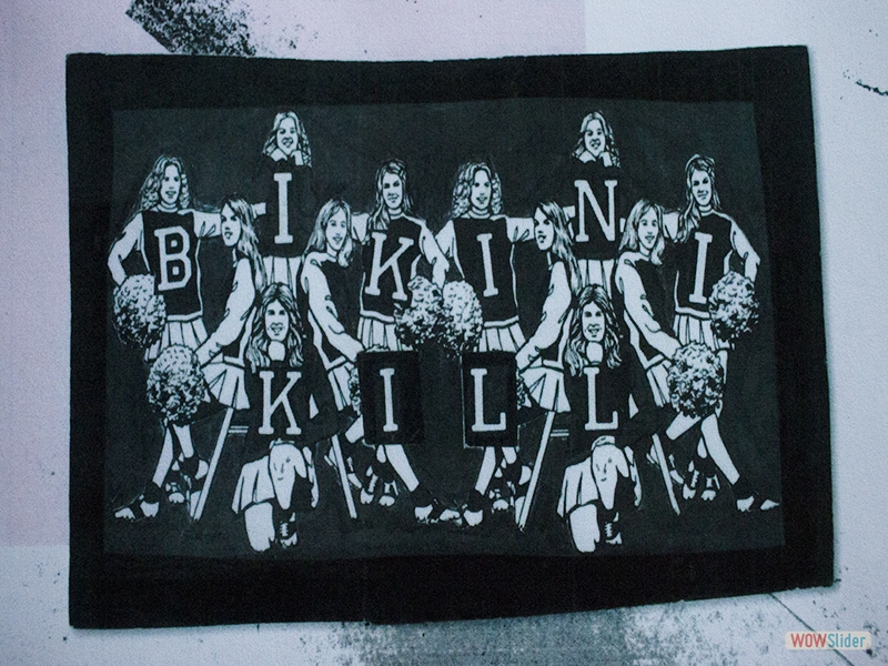 Bikini Kill art with the letters of the band spelt on cheerleader's uniforms. 
